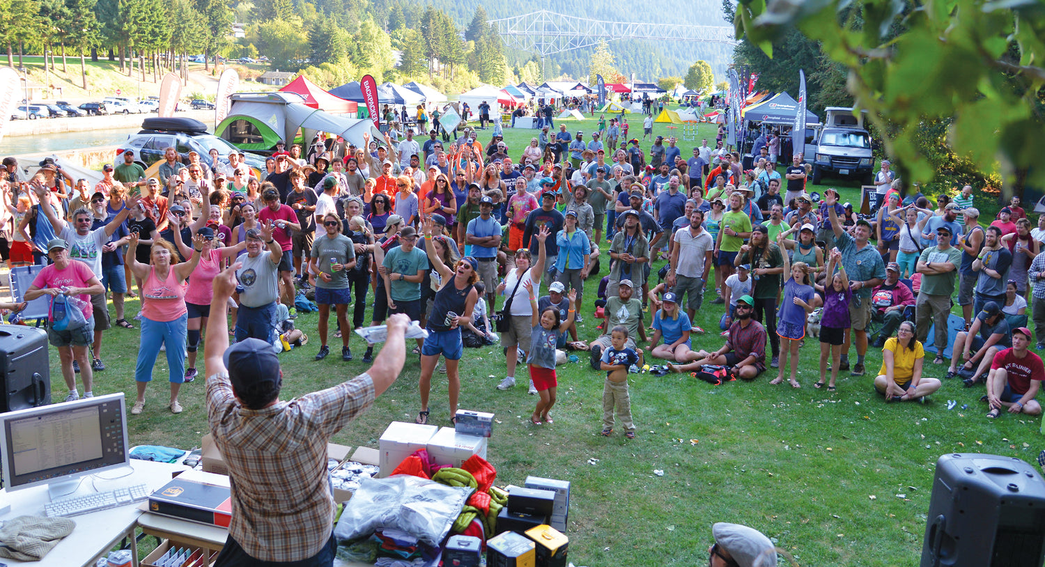 A large crowd of people reaching for prizes at a festival