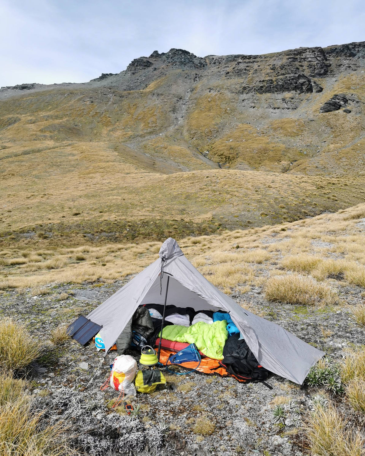 Gray Gatewood Cape pitched as a shelter with the door open on a grassy alpine slope