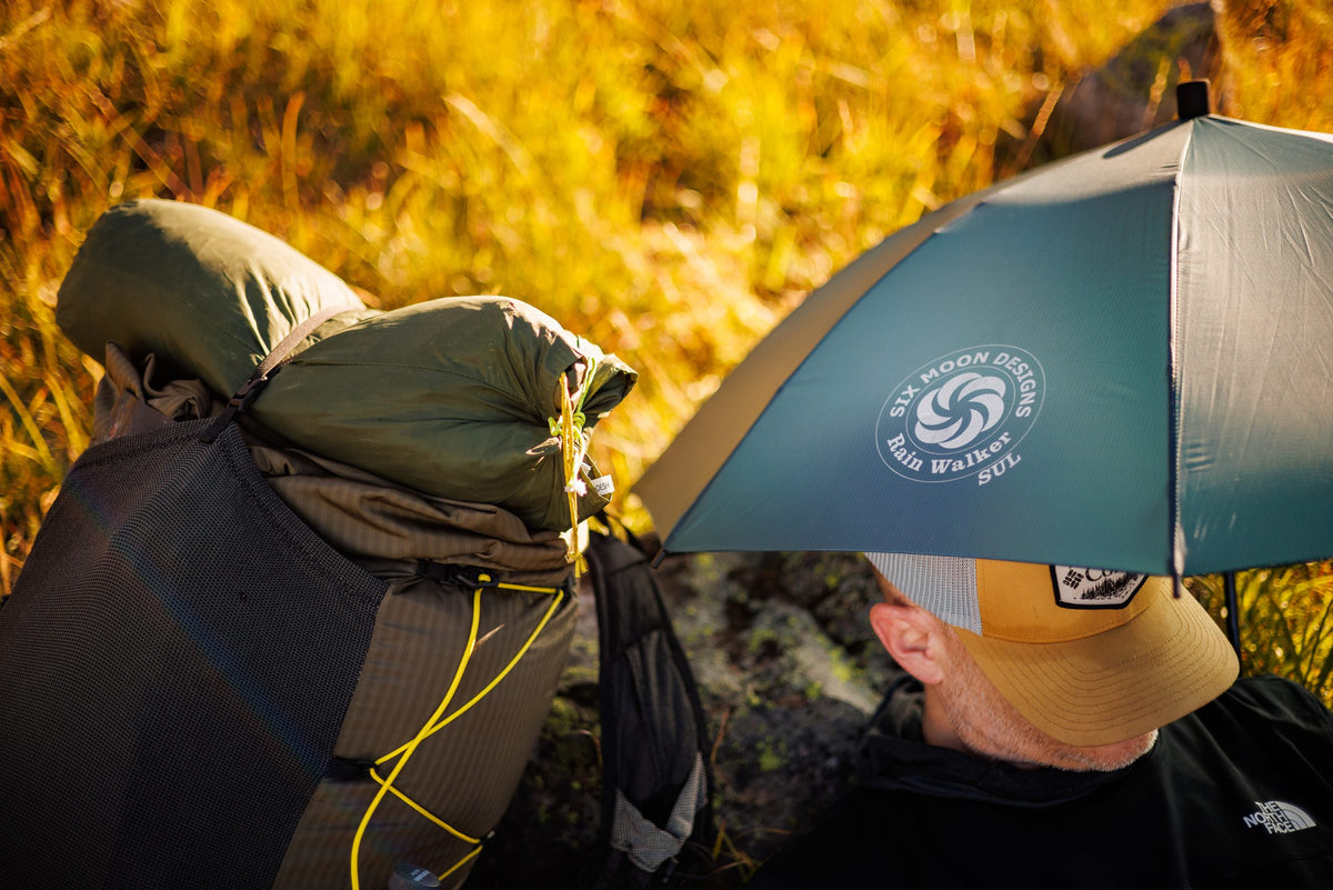 Over-the-shoulder close-up of the dark teal Rain Walker SUL umbrella and its logo
