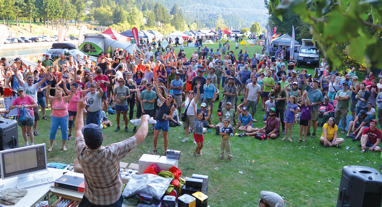 A large crowd of people reaching for prizes at a festival