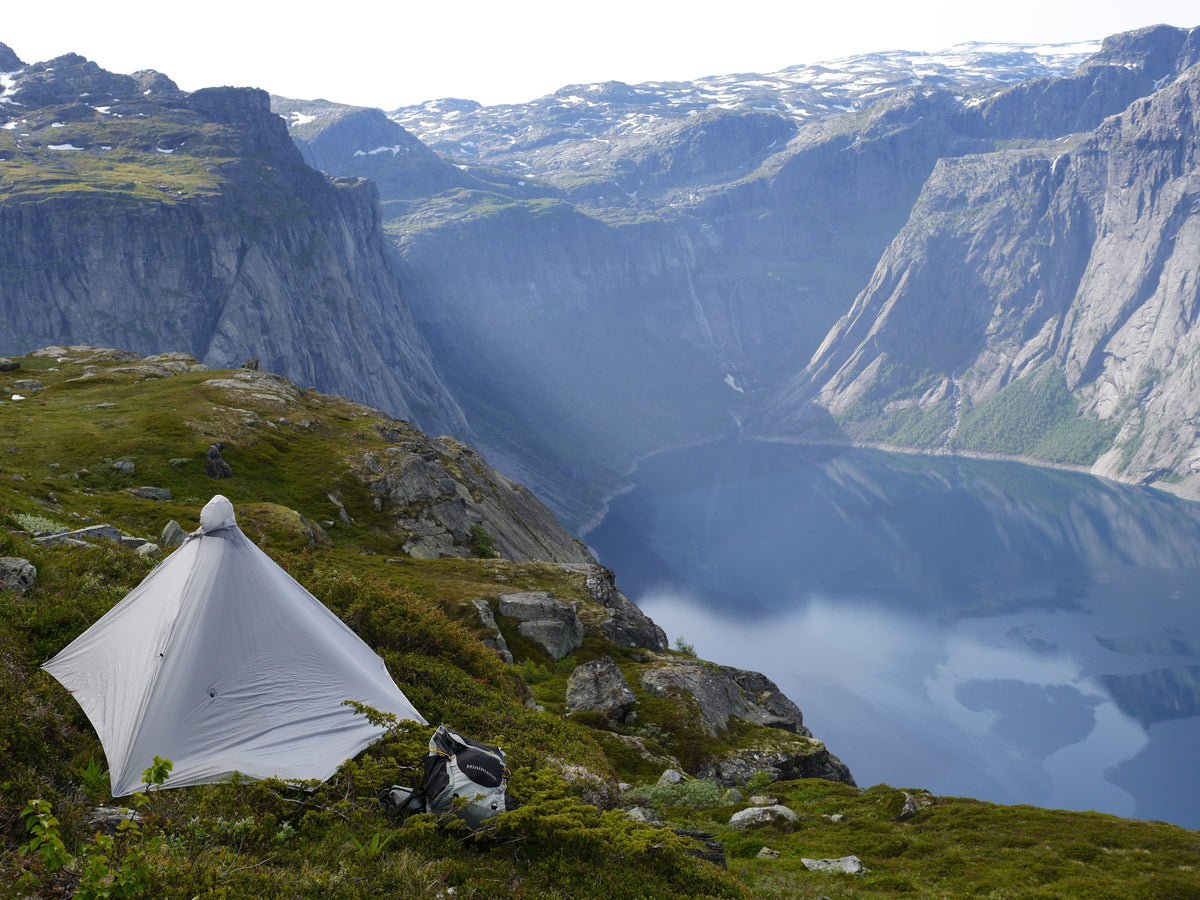 Gray Gatewood Cape shelter pitched on a cliff above a fjord near Trolltunga, Norway