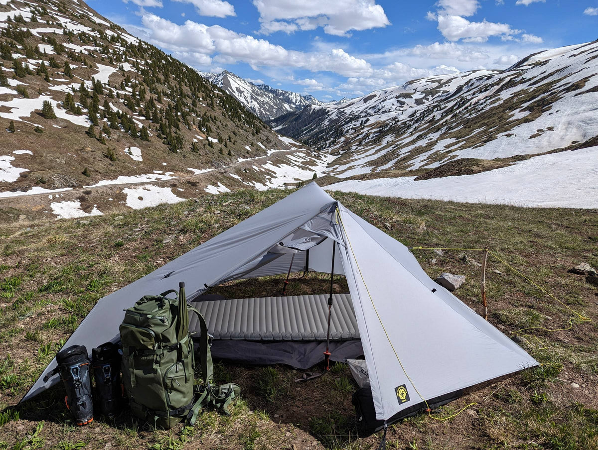 Gray Haven tent with both doors open showing the NetTent and sleeping pads, in a snowy alpine valley