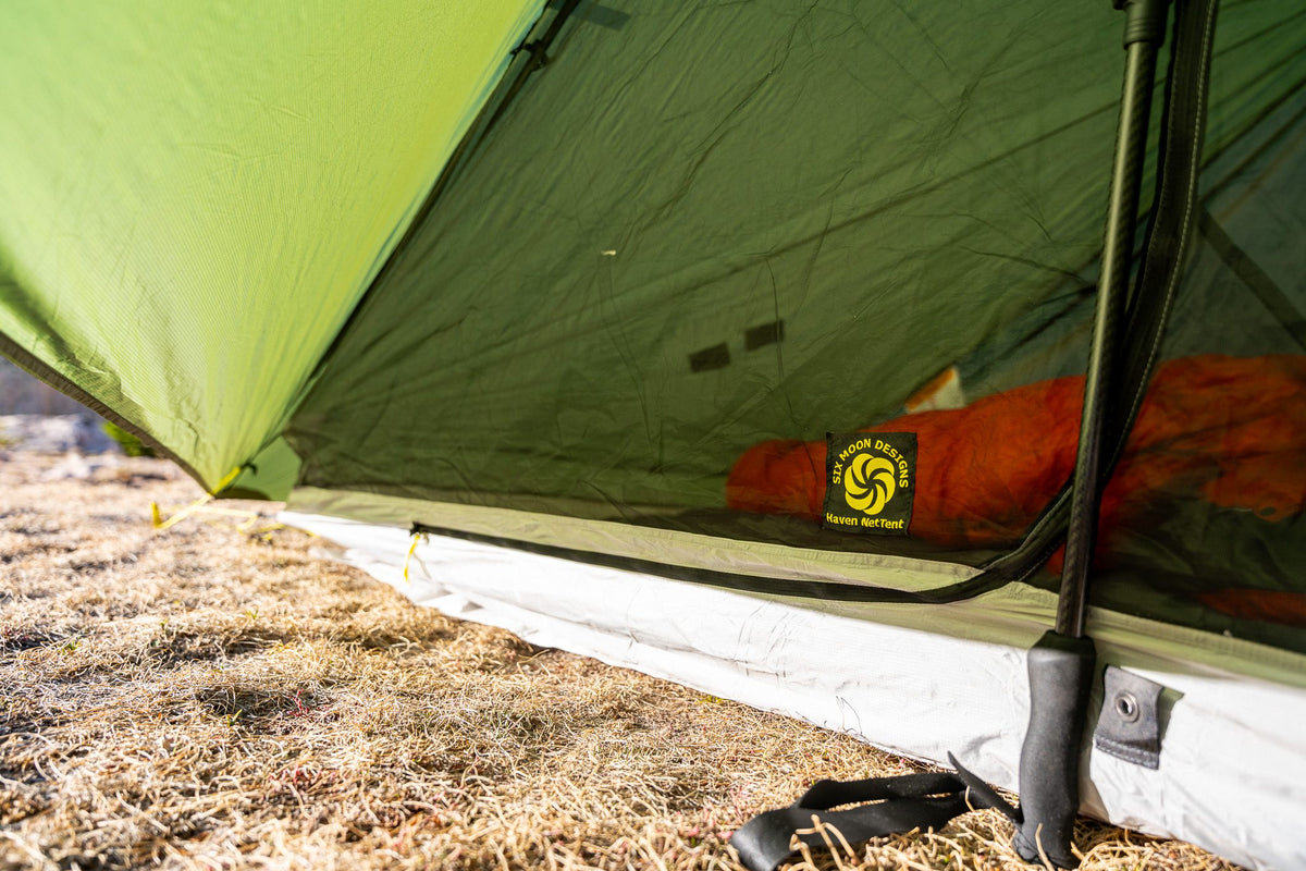 Close-up of a green Haven tent doorway with the mesh NetTent and an orange sleeping bag inside