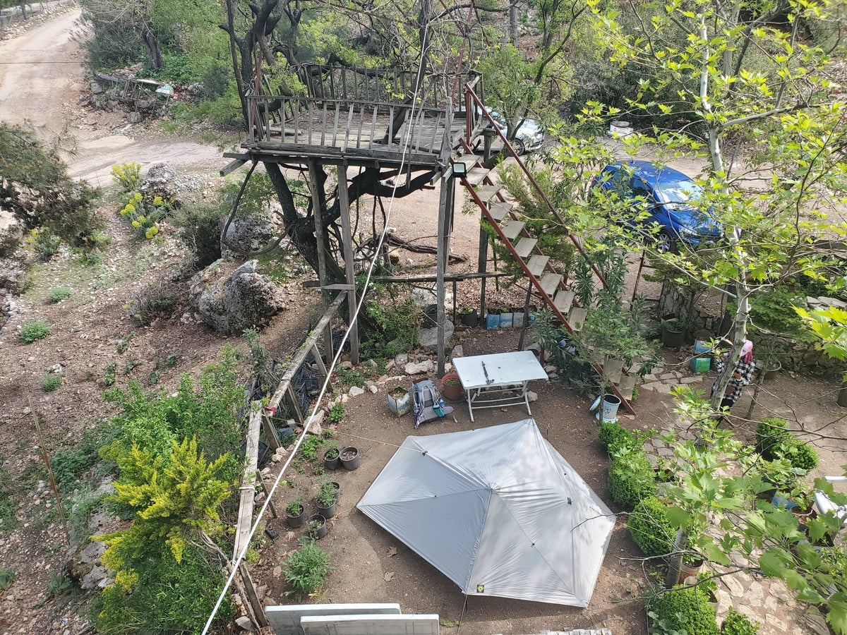 Overhead view of a gray Haven tent pitched below a wooden treehouse platform in Utah