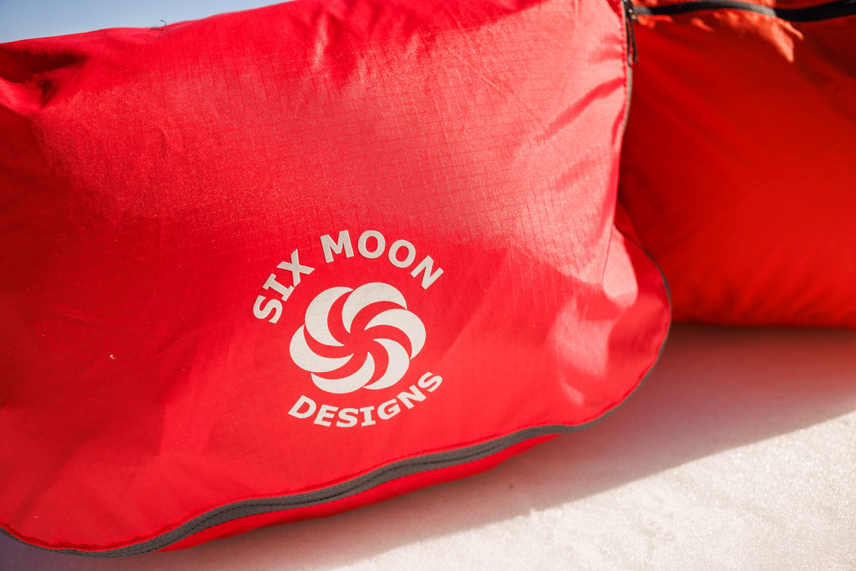 Close-up of red Six Moon Designs packing pods on snow