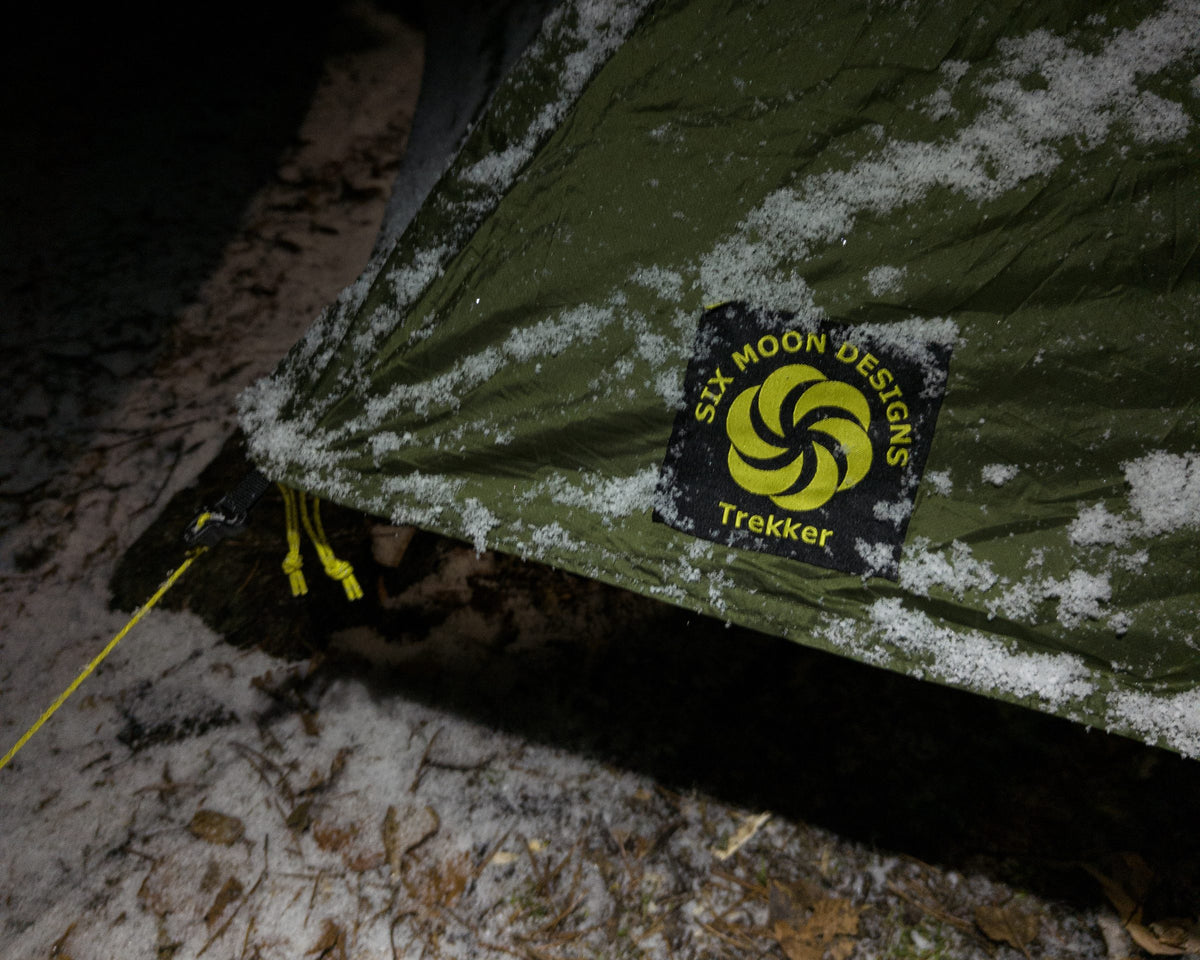 Close-up of the Skyscape Trekker logo patch on a snow-dusted fly at night